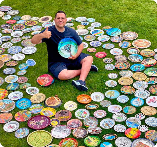 Костянтин на фоні багатьох розфарбованих тарілок